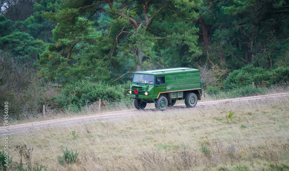 an ex-military high-mobility all-terrain utility vehicle driving an unmade countryside track, Wiltshire UK