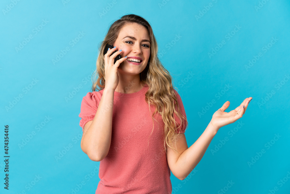 Young Brazilian woman isolated on blue background keeping a conversation with the mobile phone with someone Young Brazilian woman isolated on blue background keeping a conversation with the mobile phone with someone