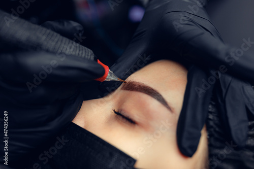 Permanent makeup tattooing of eyebrows Cosmetologist applying make up
