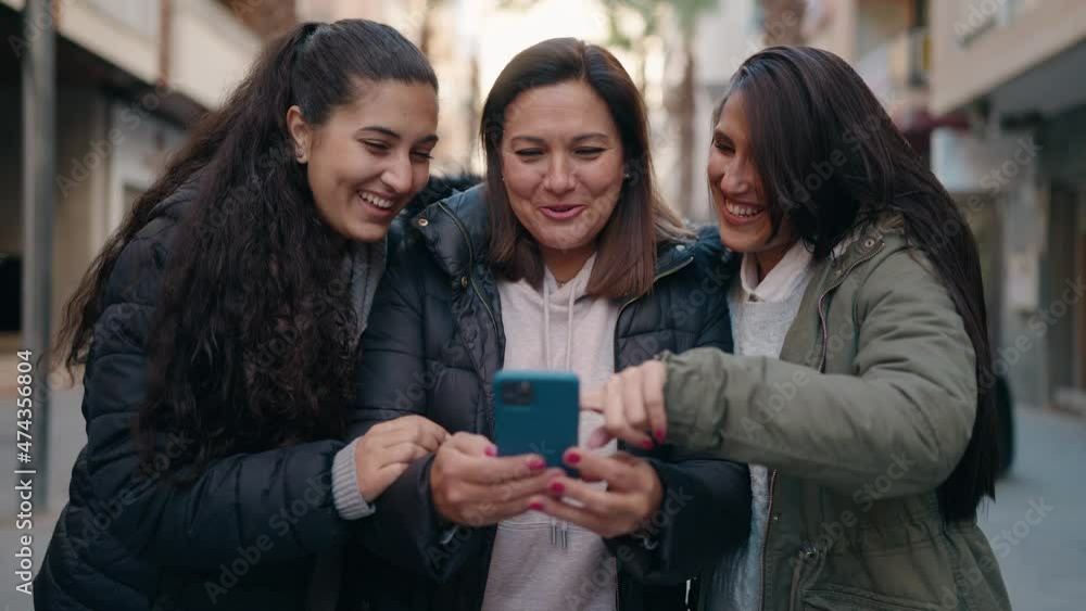 Mother and daughters smiling confident using smartphone at street Mother and daughters smiling confident using smartphone at street