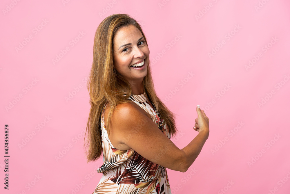 Middle age brazilian woman over isolated background pointing back Middle age brazilian woman over isolated background pointing back