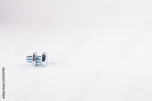 Small screw and bolt on a white background, free space. Place for advertising text. Repair of machines and equipment
