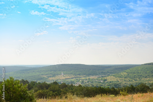 View from the mountain to the green valley with hills and forests on a summer day
