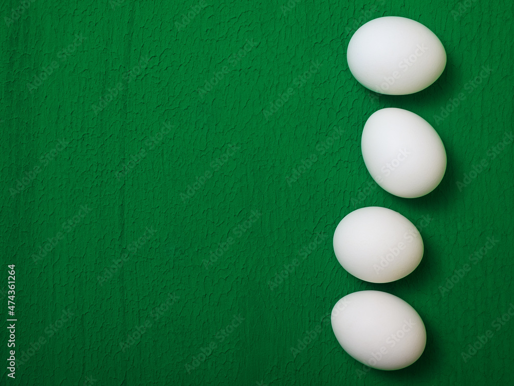 four white chicken eggs on a green background, copy space four white chicken eggs on a green background, copy space
