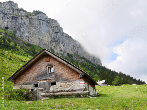 Traditional mountain hut in front of rock face. Alpstein, Switzerland.