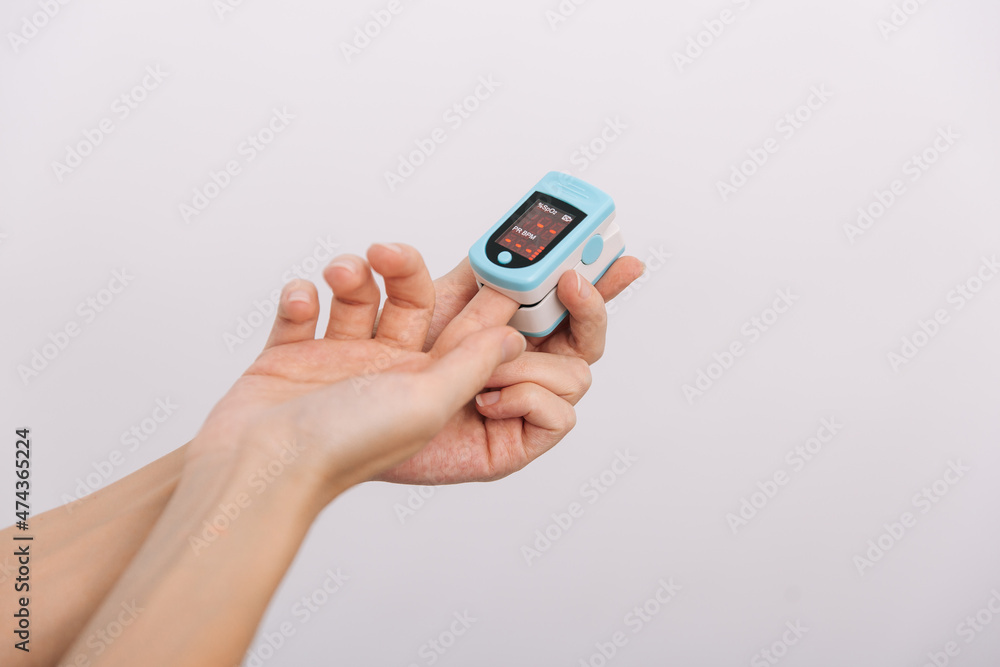 Pulse oximeter with hand of doctor isolated on white. Measuring oxygen saturation, pulse rate and oxygen levels. The concept of portable digital device to measure person's oxygen saturation. Pulse oximeter with hand of doctor isolated on white. Measuring oxygen saturation, pulse rate and oxygen levels. The concept of portable digital device to measure person's oxygen saturation.