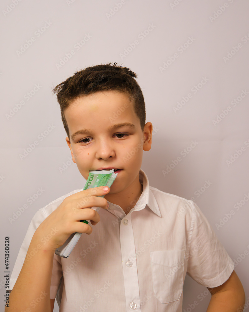 The boy tastes the money, a thoughtful look The boy tastes the money, a thoughtful look