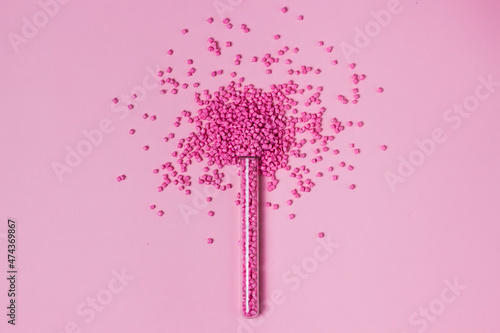 Pink granules of polypropylene or polyamide in test tube. background. Plastics and polymers industry. Monochrome