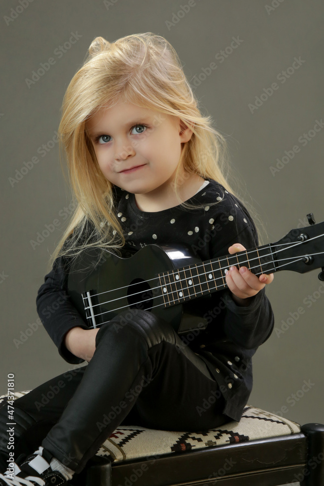 Studio portrait of adorable little girl playing ukulele Studio portrait of adorable little girl playing ukulele