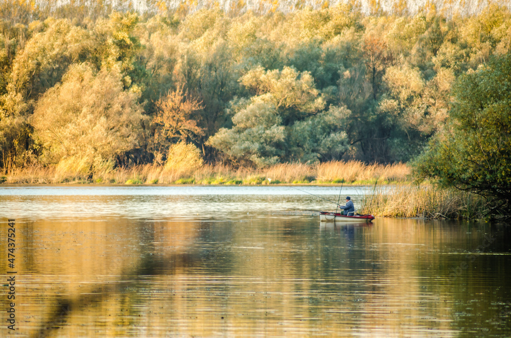 Begec, Serbia - October 30. 2021: Sport fisherman in a boat on an artificial lake near Novi Sad. Begec, Serbia - October 30. 2021: Sport fisherman in a boat on an artificial lake near Novi Sad.