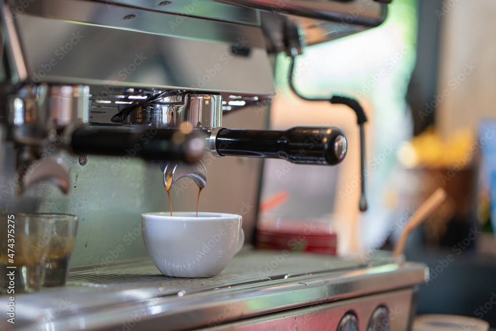 Espresso machine pours fresh black coffee closeup.