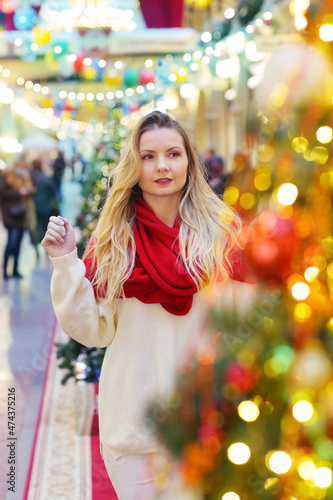 happy blond girl in red scarf close up portrait on decorated Christmas city mall background