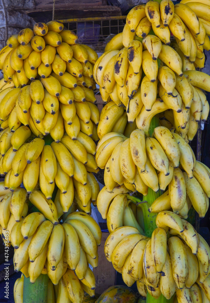 Bananas hang on the counter on branches - the main product in the market. Tanzania, Zanzibar, non-tourist market. Local market