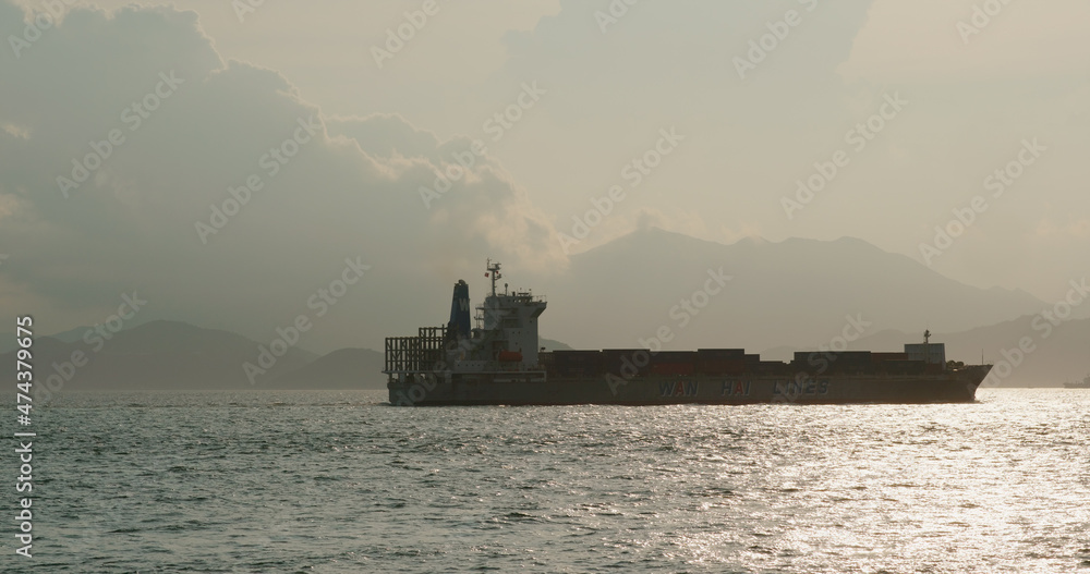 Cargo ship pass though the sea at sunset time Cargo ship pass though the sea at sunset time