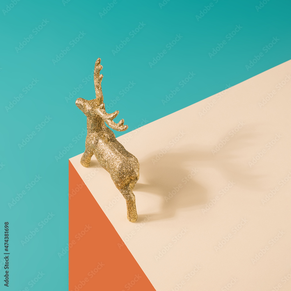 Fototapeta premium Golden reindeer figurine on a pastel surreal background. Christmas minimal concept. 
