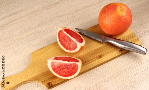 Grapefruit on a wooden cutting board with a metal knife