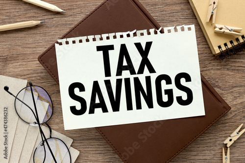 Tax Savings. text on a white paper notebook on a wooden background.