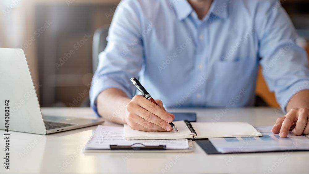 Businessman working on laptop and taking notes in office. Businessman working on laptop and taking notes in office.