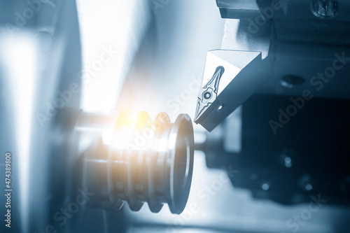 The  CNC lathe machine groove cutting the metal pulley parts with lighting  effect. photo