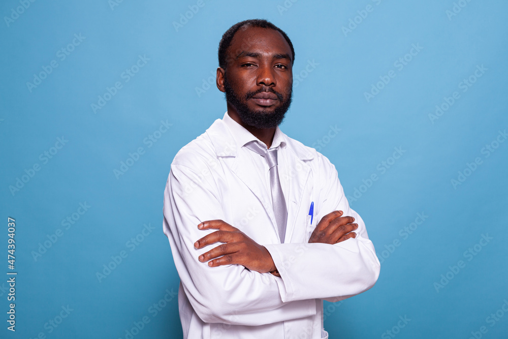 Portrait of confident medical doctor in white lab coat on blue background in photography studio. Medic in laboratory uniform posing with arms crossed. Health care professional. Portrait of confident medical doctor in white lab coat on blue background in photography studio. Medic in laboratory uniform posing with arms crossed. Health care professional.