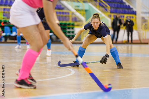 Young hockey player girl in defence against attack in indoor hockey game.