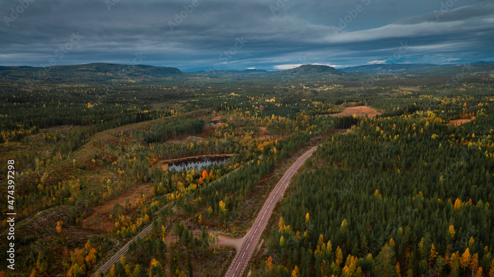 Landscape with Wildernes Road through forest in autumn in Lapland in Sweden from above, colored trees and clouds in sky. Landscape with Wildernes Road through forest in autumn in Lapland in Sweden from above, colored trees and clouds in sky.