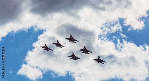 A link of jet military, fighters, aircraft are performing a maneuver against the background of a blue sky
