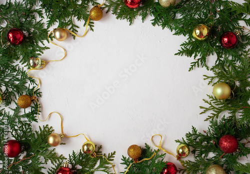 Christmas or New Year background: fir branches on a white background with Christmas balls. White frame for congratulations