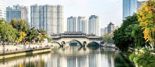 The famous Anshun Bridge with surrounding Autumn scenery and buildings in the background reflected in the Jinjiang River of Chengdu, a super city in Sichuan, China photo