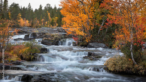 Trappstegsforsen waterfall in autumn along the Wilderness Road in Lapland in Sweden  clouds in the sky.