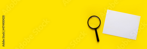 magnifying glass and blank white sheet on a yellow background. Banner