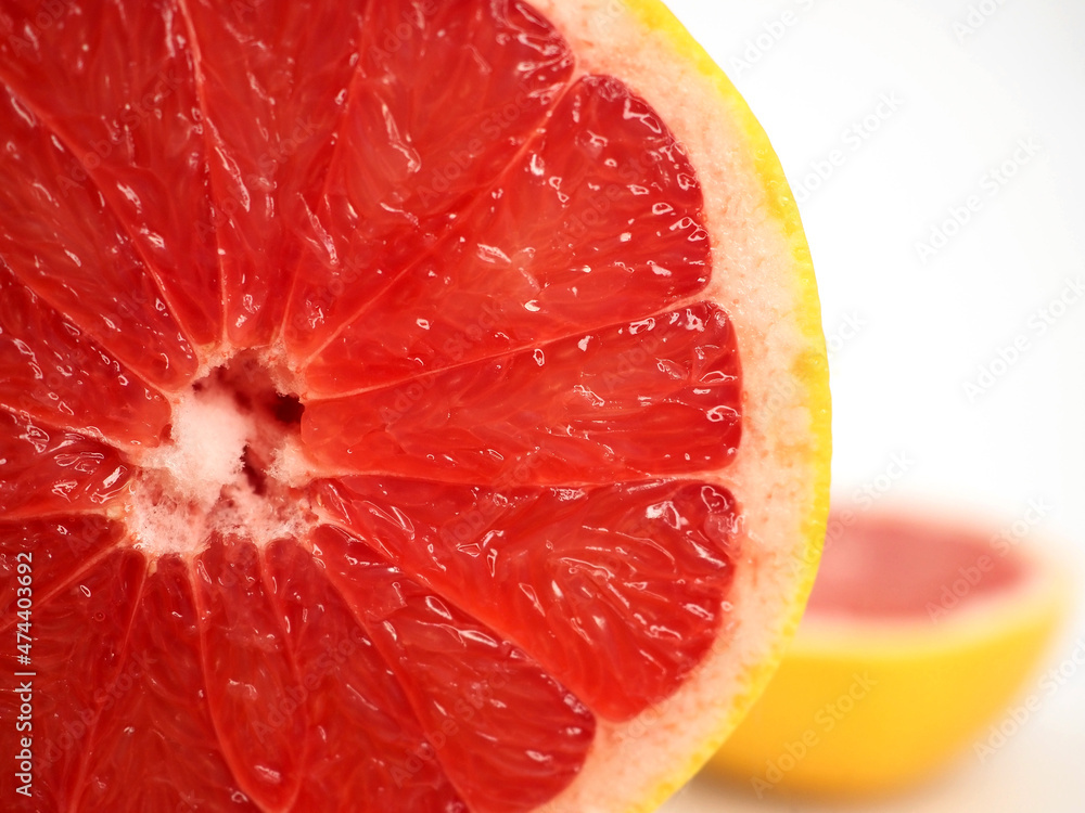 Red grapefruit cut in half. Juicy red pulp and rind. Large segment against the background of the second half of citrus