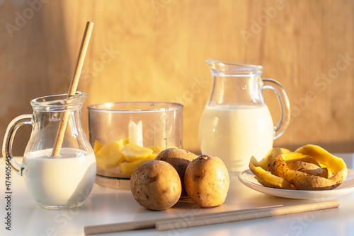 Vegan plant milk from potato in glass jar and potato tubers on the table. Concept of potato milk, vegan sustainable option, plant-based dairy. Substitute drink, healthy eating, diet, nutrition