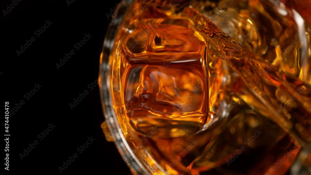 Super Slow Motion Detail Shot of Pouring Whiskey on Ice Cubes into Glass at 1000fps. Super Slow Motion Detail Shot of Pouring Whiskey on Ice Cubes into Glass at 1000fps.