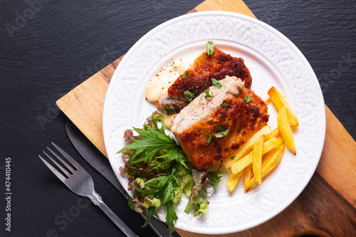 Food concept Homemade Veal cordon bleu with salad and french fried in white ceramic plate on wooden board and black slate stone background with copy space photo