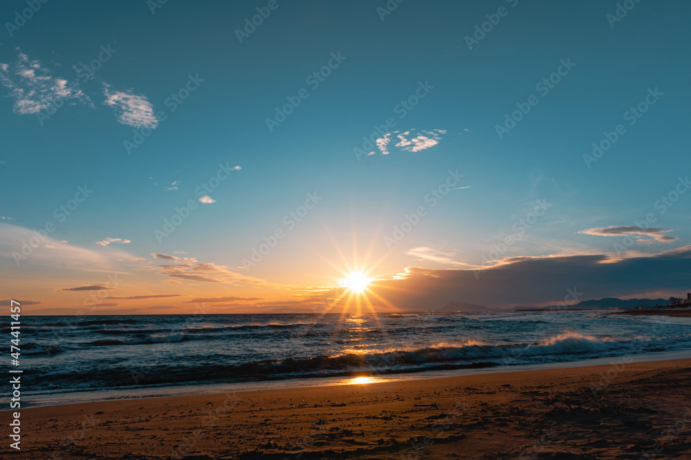 Sunrise or sunset on the beach, with clouds in the sky and mountains on the horizon. Sunrise or sunset on the beach, with clouds in the sky and mountains on the horizon.
