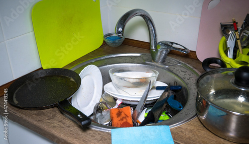 A lot of dirty dishes in the kitchen sink, huge heap of dirty dishes waiting for the flatmate photo