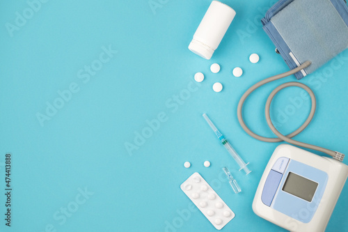 Medical concept, flat, lying on a blue background. Space for copying. Tonometer, pills, syringe on blue, top view