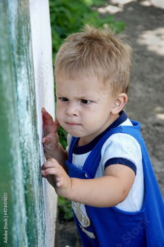 Portrait of child. Little boy focused, trying to open the door. Outdoor. Summer. photo