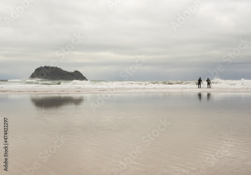 Surfers on the beach of Zarautz with Getaria in the background, Euskadi photo