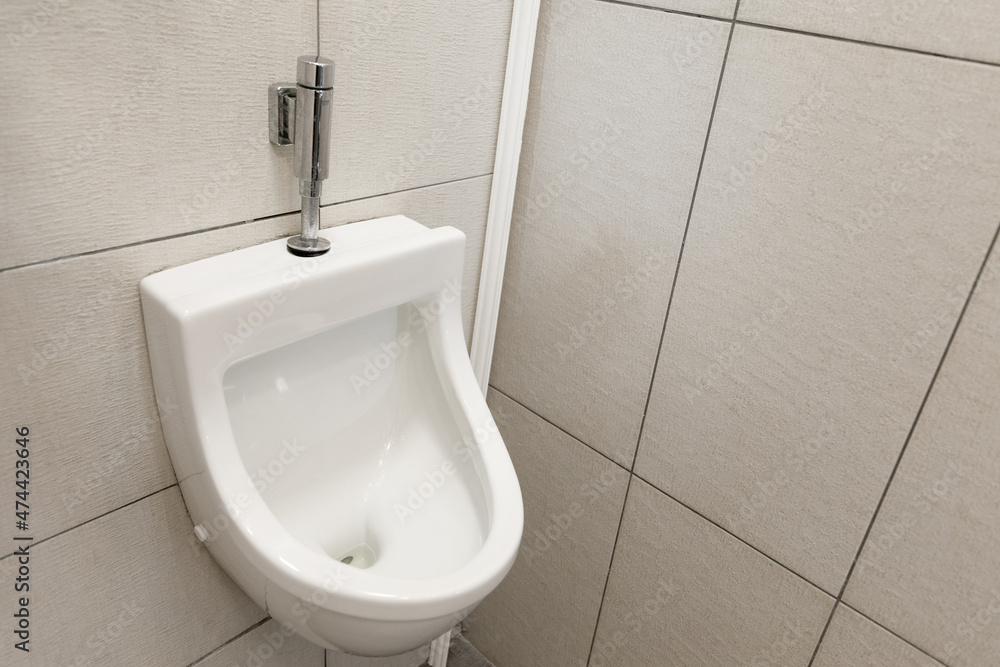 Fototapeta premium Men's room in the toilet, white tiled urinal on the wall.