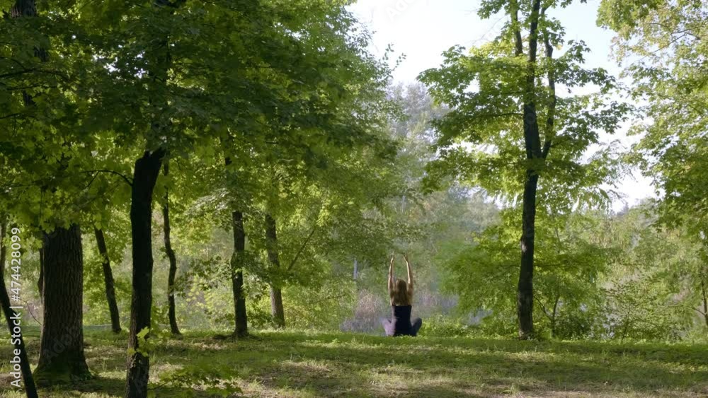 Silhouette woman raising arms in air. Woman practices yoga at sunrise in forest. Woman performing a spiritual yoga pose. Concept of fitness, healthy lifestyle Silhouette woman raising arms in air. Woman practices yoga at sunrise in forest. Woman performing a spiritual yoga pose. Concept of fitness, healthy lifestyle