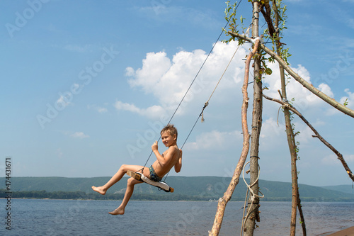 A boy on the beach swinging on a swing. Summer sunny day.
