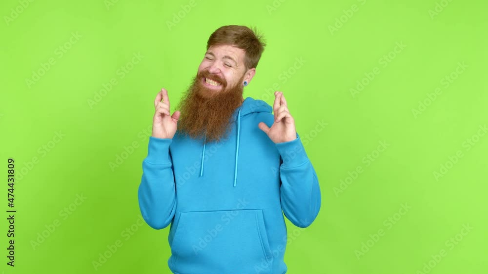 Redhead man with long beard with fingers crossing and wishing the best. Making a wish over isolated background Redhead man with long beard with fingers crossing and wishing the best. Making a wish over isolated background