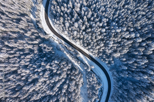 Natural winter landscape from air. Aerial view on the road and forest at the winter time. Winter chill. Forest and snow. The photo is in high resolution.