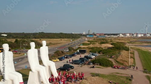 Aerial view flying near Man Meets The Sea, a colossal monument on Esbjerg coastline in Denmark. Drone view flying over the giant landmark visited by numerous tourists photo