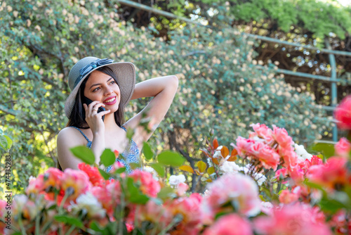 Young woman talking on the phone at park during spring summer season in vacations