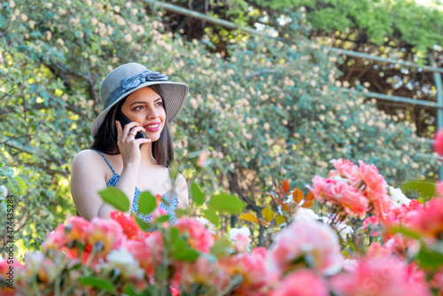 Young woman talking on the phone at park during spring summer season in vacations