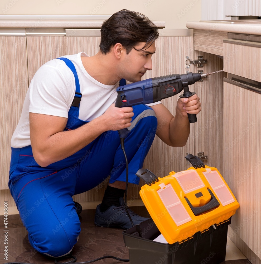 Young repairman working at the kitchen Young repairman working at the kitchen