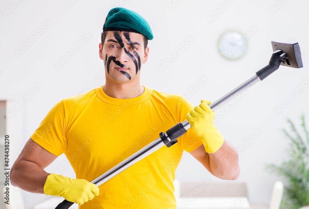 Funny man in military style cleaning the house Funny man in military style cleaning the house